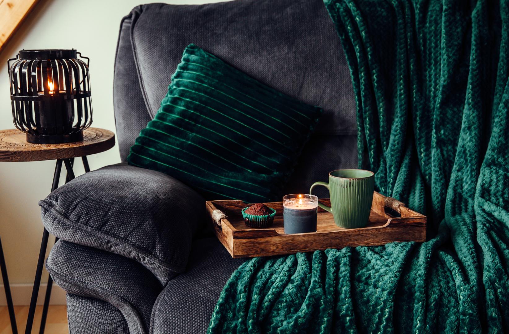 Cosy sofa with a blanket, a mug of tea and candles