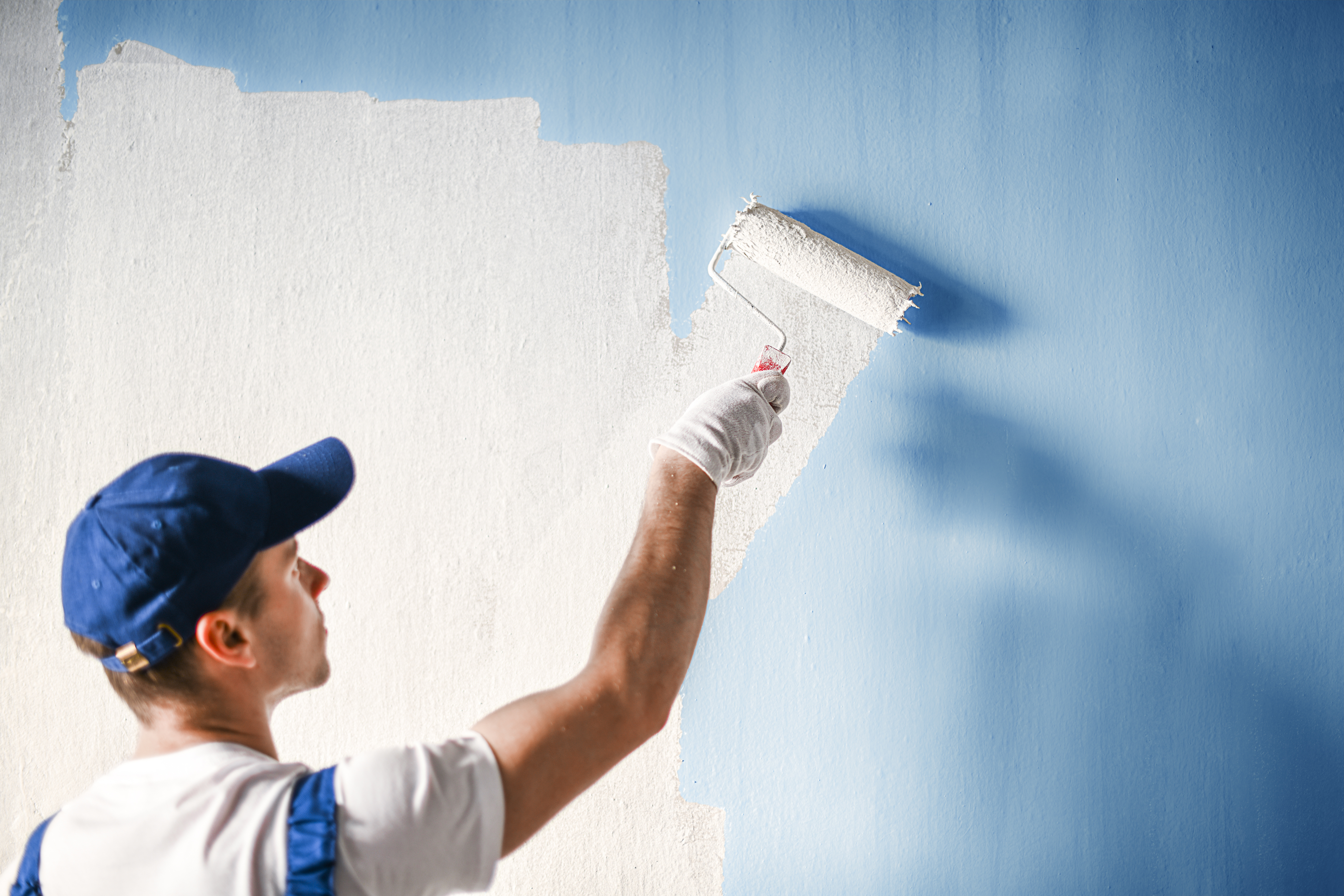man DIY painting blue walls white