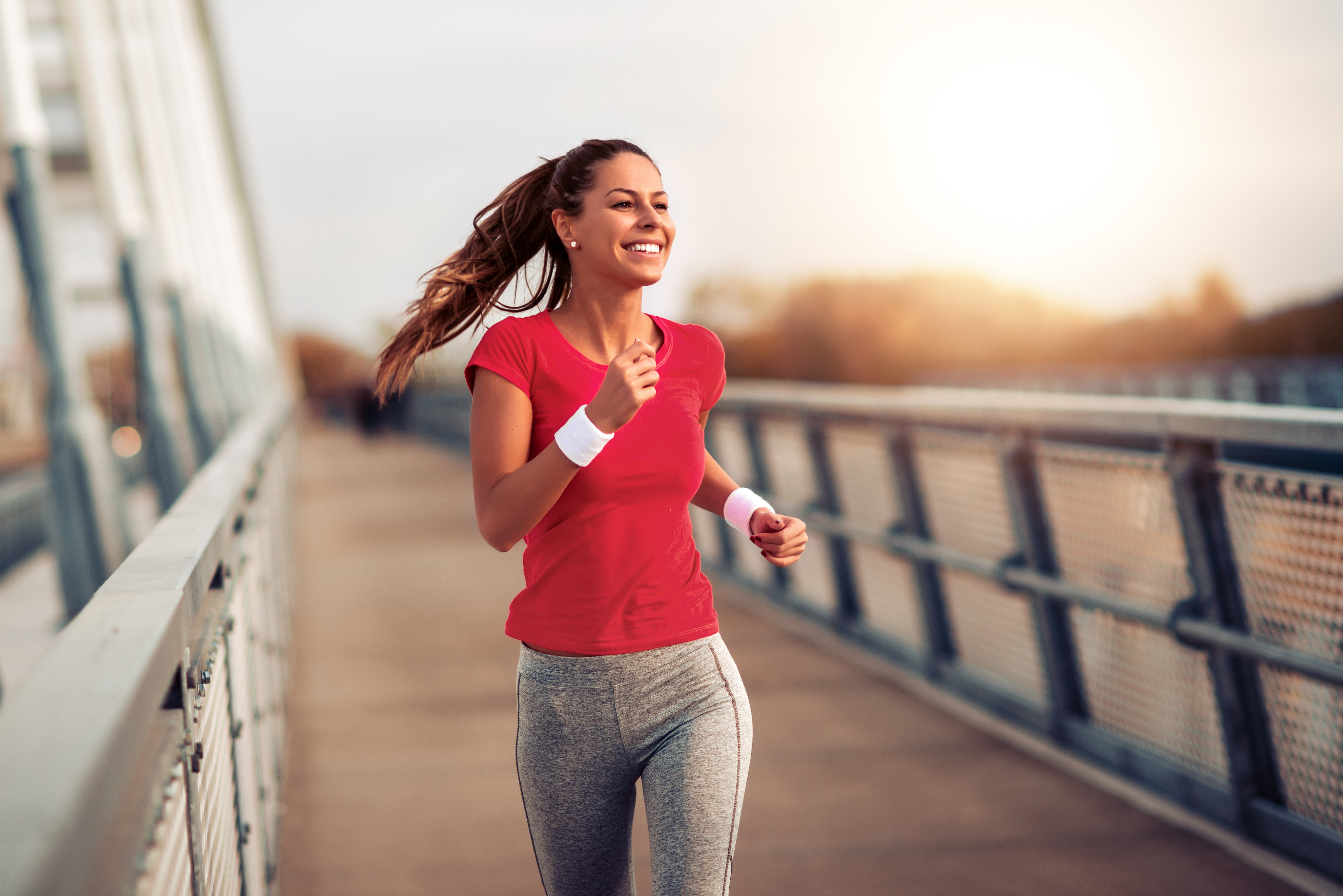 happy woman running excercising on her commute on a bridge by the water