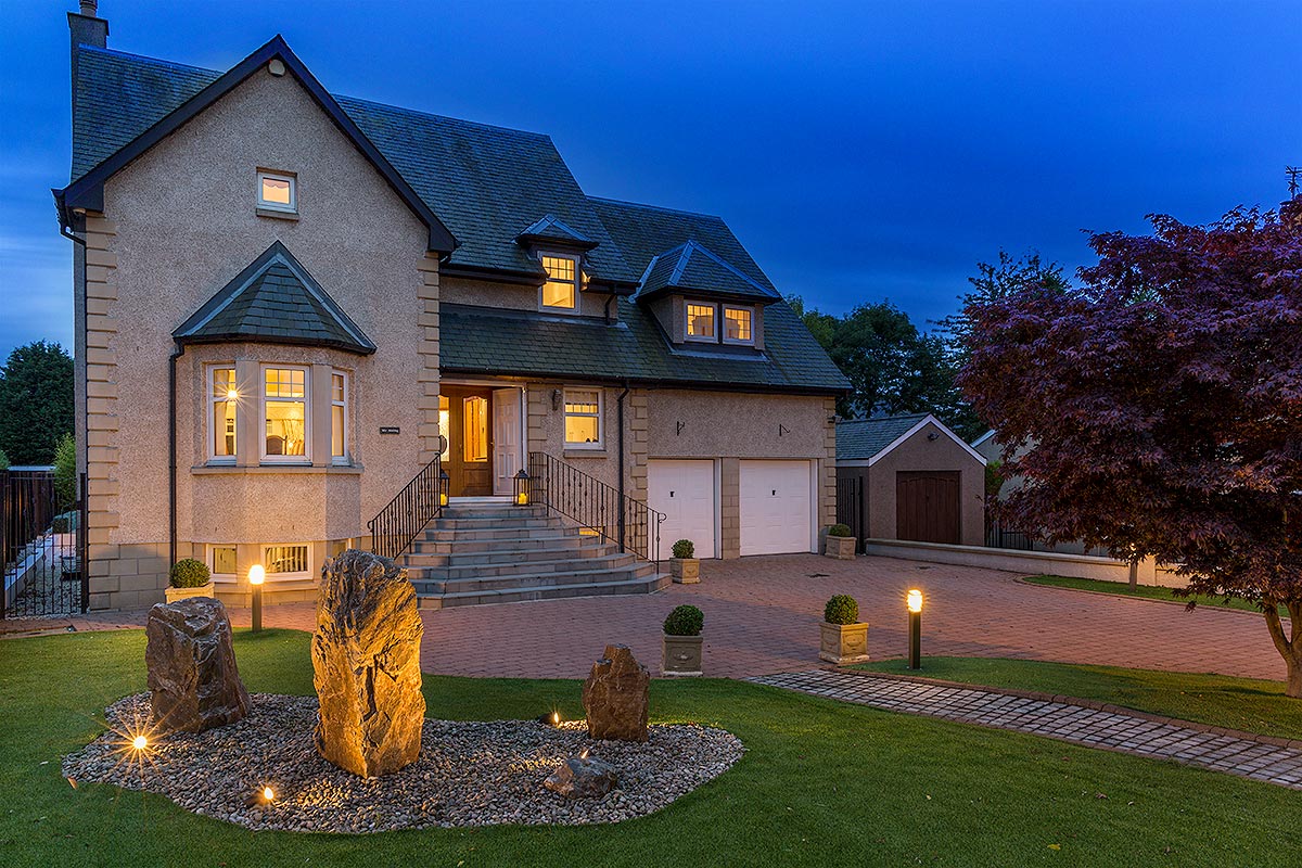 unique pebble large family home with landscaped front garden night with lights