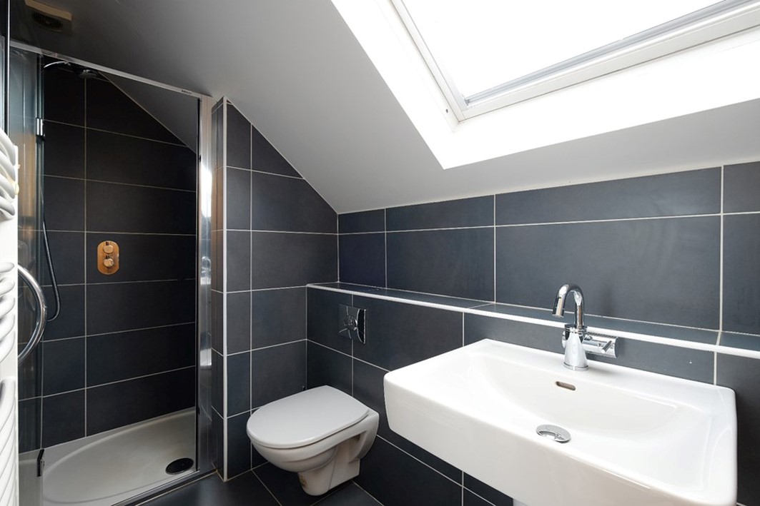 dark grey tile stylish simple loft bathroom with skylight